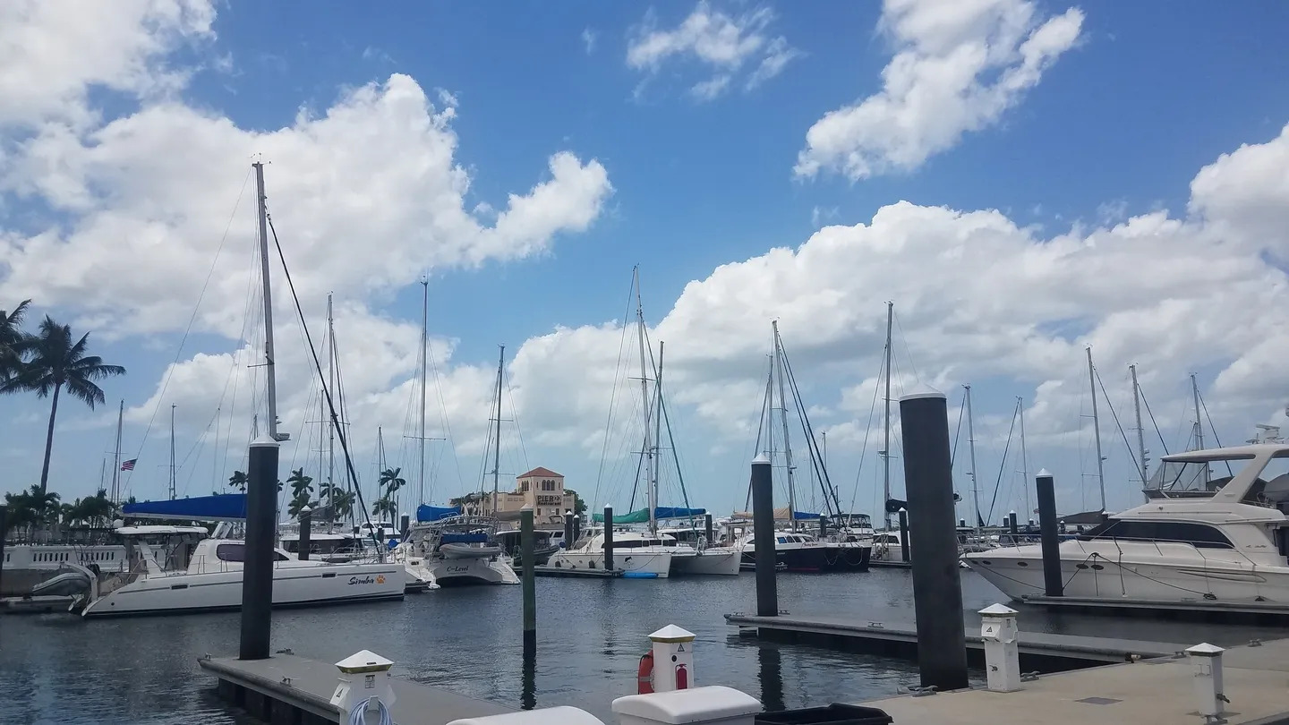 A harbor filled with lots of boats under a cloudy blue sky.