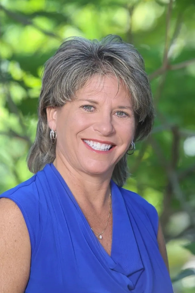 A woman in blue shirt smiling for the camera.